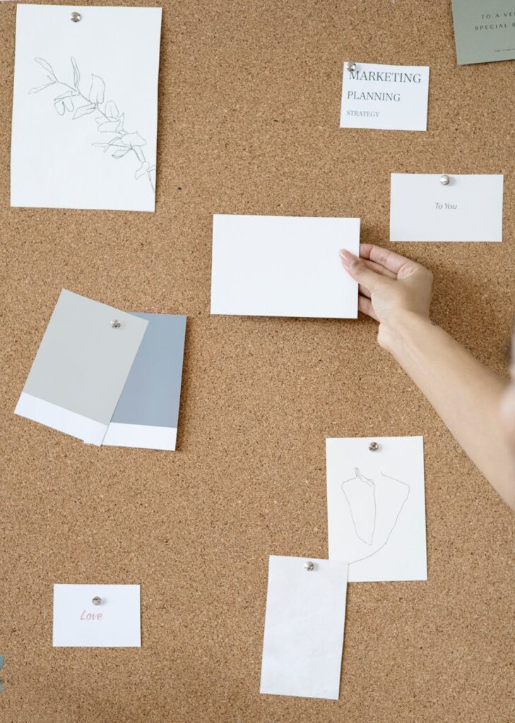 Corkboard with notes and hands showcasing creative planning in an office setting.
